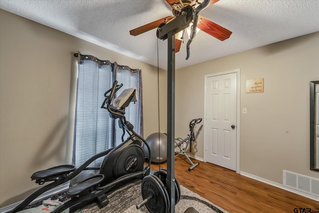 exercise room featuring ceiling fan, a textured ceiling, and hardwood / wood-style flooring