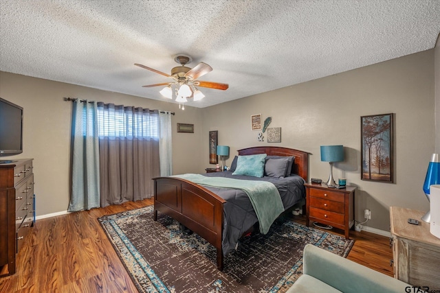 bedroom with a textured ceiling, ceiling fan, and dark wood-type flooring