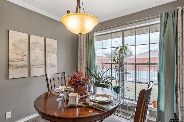 dining room with a water view, ornamental molding, and a textured ceiling