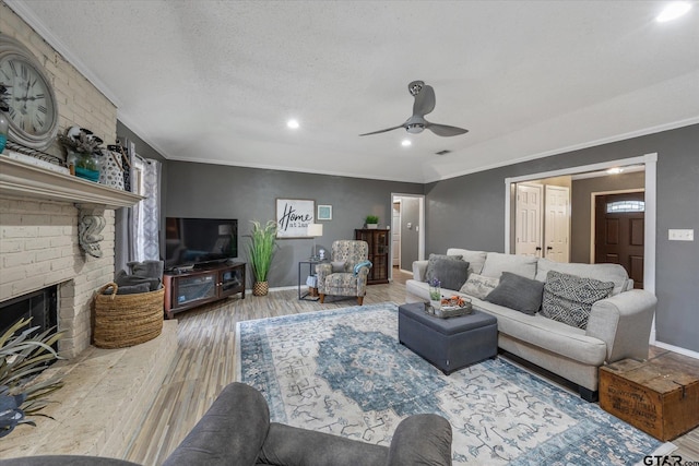 living room featuring a brick fireplace, ornamental molding, a textured ceiling, ceiling fan, and hardwood / wood-style flooring