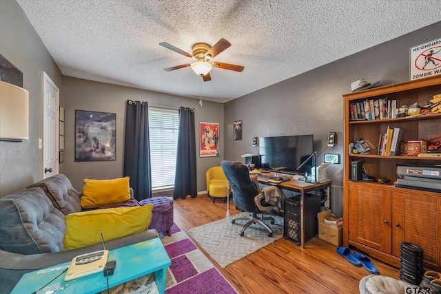 home office with a textured ceiling, light wood-type flooring, and ceiling fan