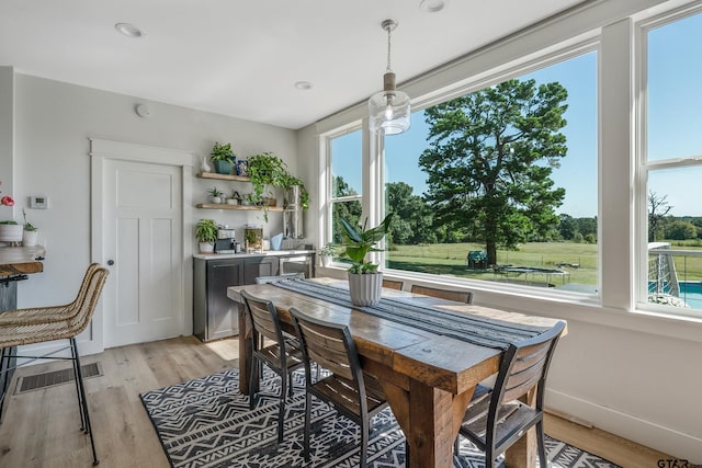 dining room with visible vents, plenty of natural light, baseboards, and light wood finished floors