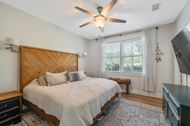 bedroom featuring visible vents, baseboards, light wood-style flooring, and a ceiling fan