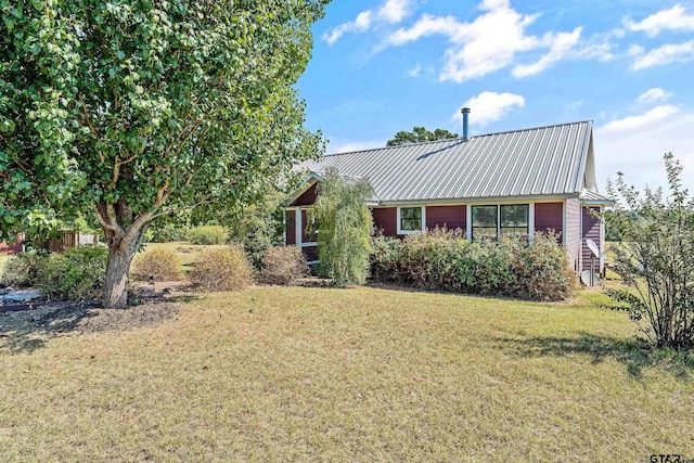 view of front of house featuring metal roof and a front lawn