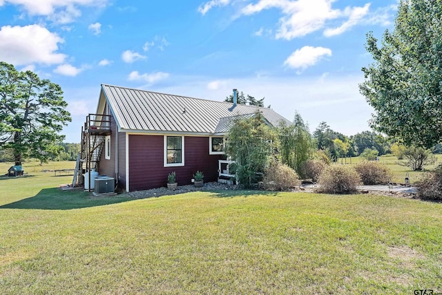 view of side of home with a yard, metal roof, cooling unit, and a standing seam roof