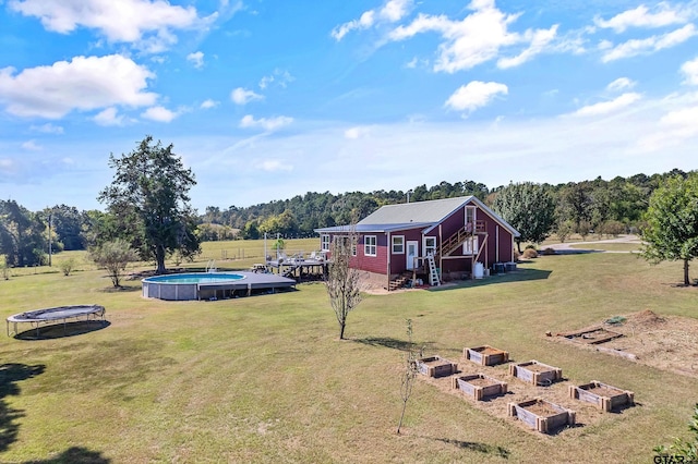 view of yard featuring a vegetable garden, an outdoor pool, and a trampoline