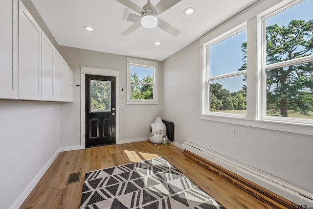 entryway with a baseboard heating unit, baseboards, visible vents, and light wood-type flooring