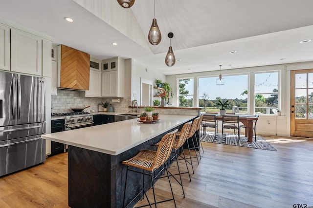 kitchen featuring a breakfast bar, a peninsula, stainless steel appliances, decorative backsplash, and light countertops