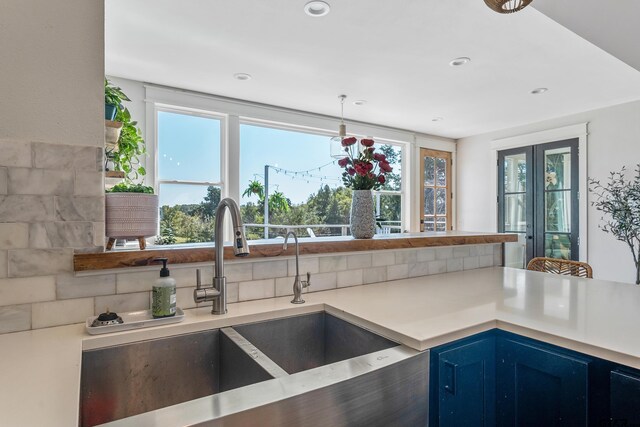 kitchen with recessed lighting, light countertops, blue cabinets, and a sink