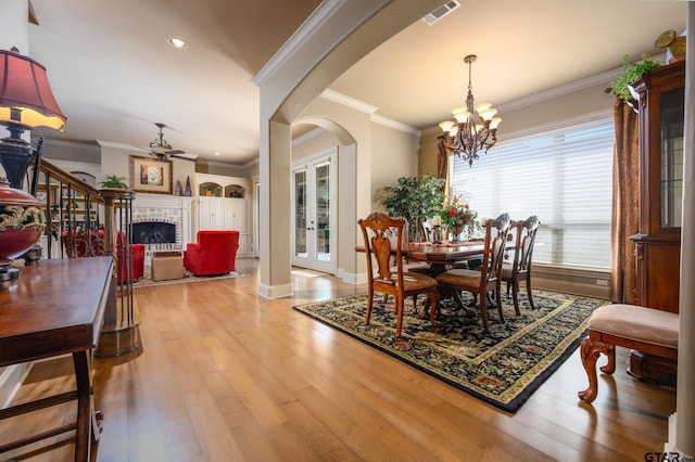 7022 Walden Dr, Tyler, TX 75703 - dining area with wood finished floors, arched walkways, a chandelier, a ceiling fan, and a fireplace