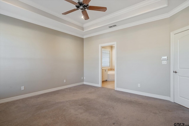 spare room with ceiling fan, light carpet, ornamental molding, and a tray ceiling