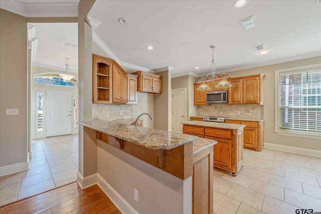 kitchen with a kitchen breakfast bar, kitchen peninsula, decorative backsplash, pendant lighting, and appliances with stainless steel finishes