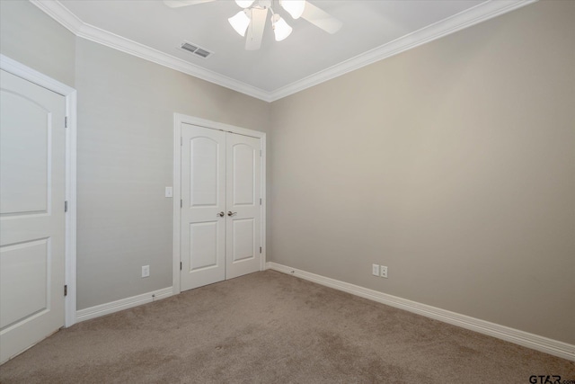 unfurnished bedroom featuring ornamental molding, carpet floors, ceiling fan, and a closet