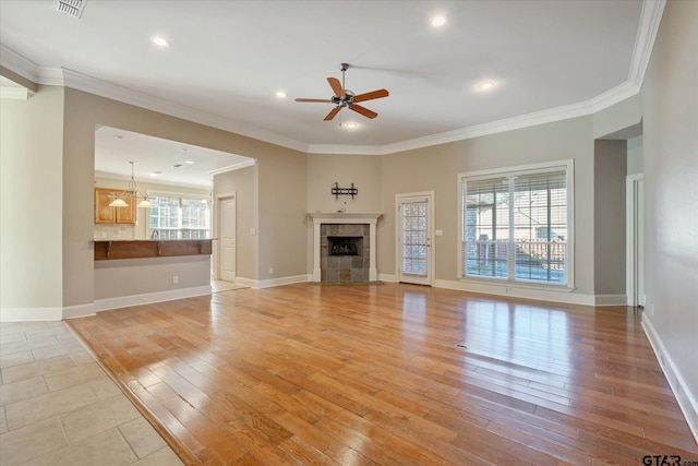 unfurnished living room with a fireplace, ornamental molding, ceiling fan, and light wood-type flooring