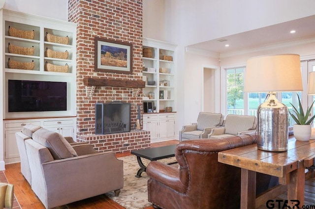 living room with light wood-style floors, a fireplace, crown molding, and a high ceiling