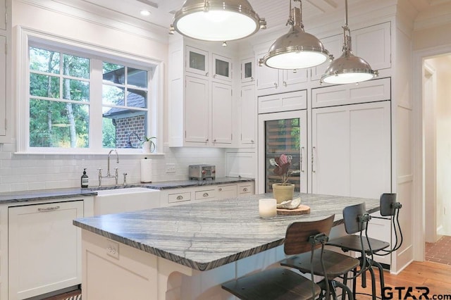 kitchen with a kitchen breakfast bar, a kitchen island, white cabinetry, and pendant lighting