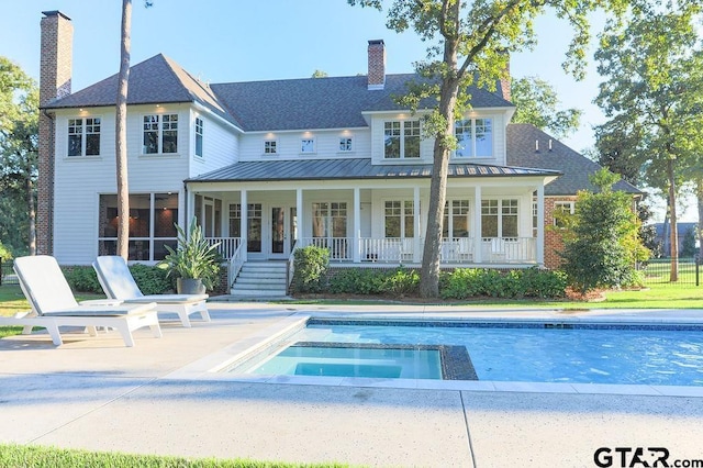 back of property featuring a standing seam roof, a patio area, metal roof, and a chimney