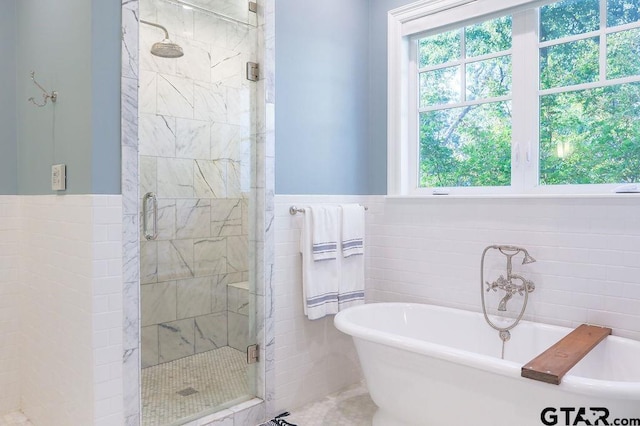 full bathroom with tile walls, wainscoting, a freestanding bath, and a shower stall