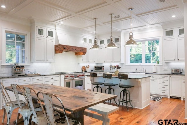 kitchen with a center island, double oven range, custom range hood, and white cabinetry