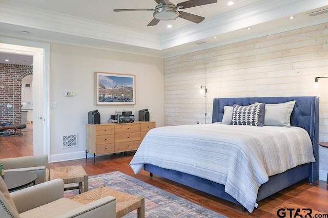 bedroom with arched walkways, ornamental molding, dark wood finished floors, and visible vents