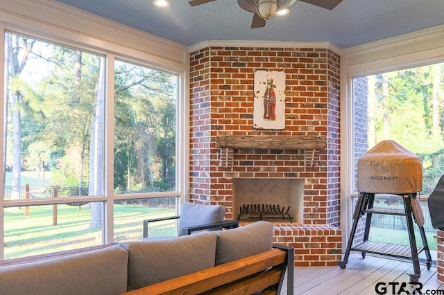 living room with a healthy amount of sunlight, a fireplace, light wood-style flooring, and crown molding