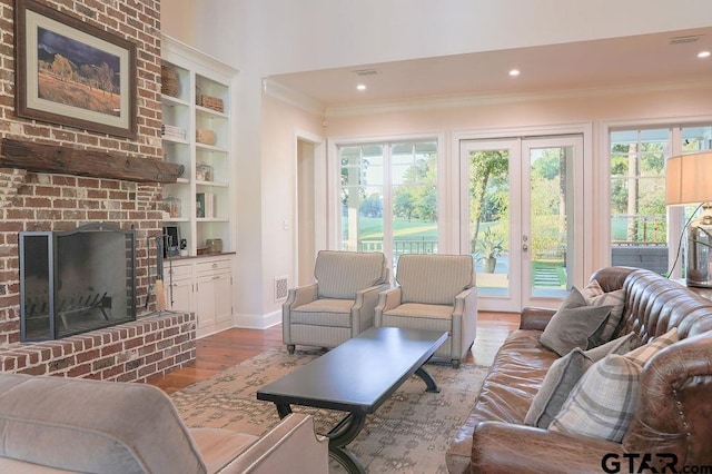 living area featuring visible vents, ornamental molding, wood finished floors, french doors, and a brick fireplace