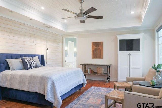 bedroom with crown molding, a tray ceiling, dark wood-type flooring, and recessed lighting