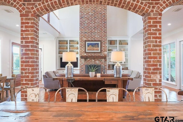 dining room with built in shelves, a high ceiling, visible vents, decorative columns, and crown molding