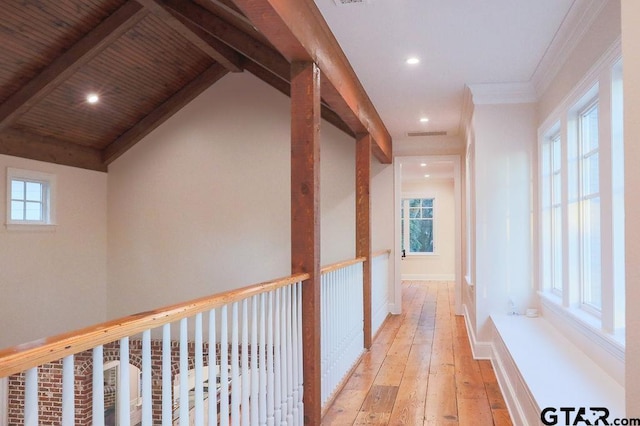 hallway featuring light wood-type flooring, a healthy amount of sunlight, lofted ceiling with beams, and baseboards