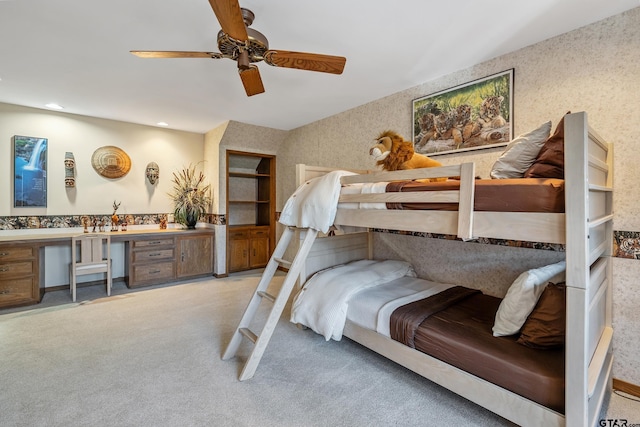 carpeted bedroom with wallpapered walls, a ceiling fan, built in desk, and recessed lighting