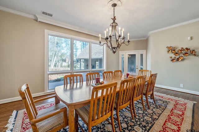 dining space featuring hardwood / wood-style flooring, baseboards, ornamental molding, and an inviting chandelier