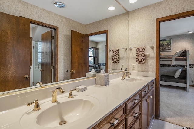 ensuite bathroom featuring a sink, connected bathroom, and wallpapered walls