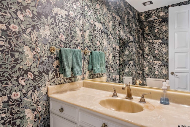 bathroom with vanity, toilet, and wallpapered walls