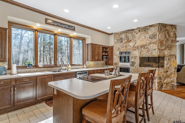 kitchen with double wall oven, light countertops, electric cooktop, decorative backsplash, and a sink