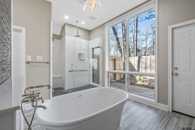 bathroom featuring recessed lighting, a freestanding tub, and a shower stall