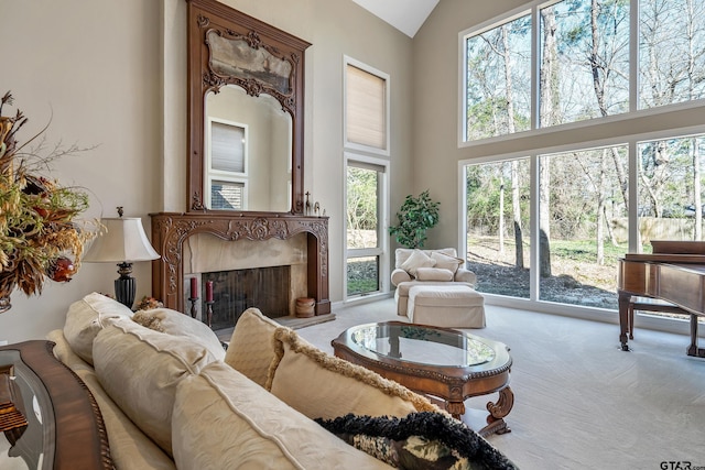 carpeted living room with high vaulted ceiling and a high end fireplace