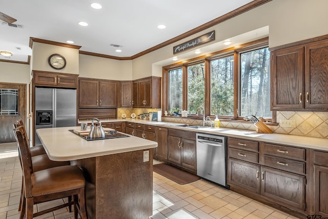 kitchen featuring a breakfast bar area, black electric stovetop, stainless steel dishwasher, refrigerator with ice dispenser, and a sink