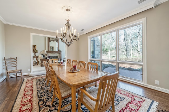 dining room with dark wood-style floors, ornamental molding, and a glass covered fireplace