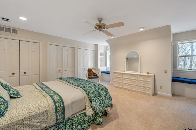 bedroom featuring light carpet, baseboards, visible vents, and two closets