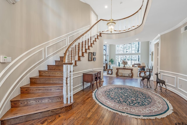 foyer entrance with stairs, an inviting chandelier, hardwood / wood-style flooring, and a decorative wall