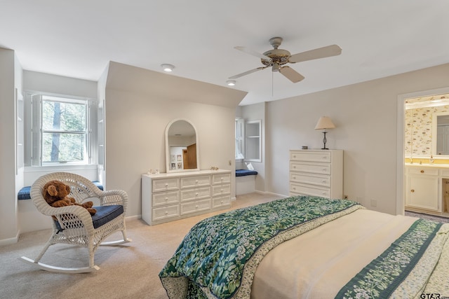 bedroom featuring baseboards, ensuite bathroom, a ceiling fan, and light colored carpet