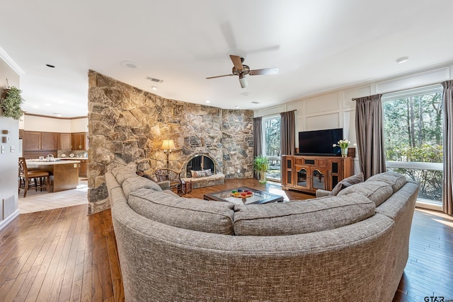 living area with ceiling fan, plenty of natural light, wood-type flooring, and crown molding