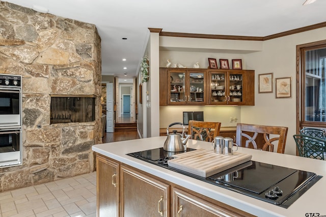 kitchen featuring double oven, brown cabinets, light countertops, and crown molding