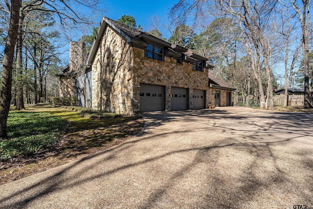 view of side of home with a garage, stone siding, and concrete driveway