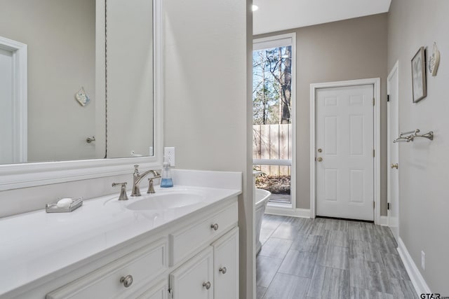 bathroom with baseboards, a freestanding bath, and vanity