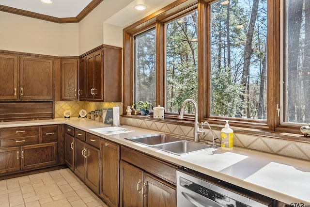 kitchen featuring a sink, light countertops, ornamental molding, backsplash, and dishwasher