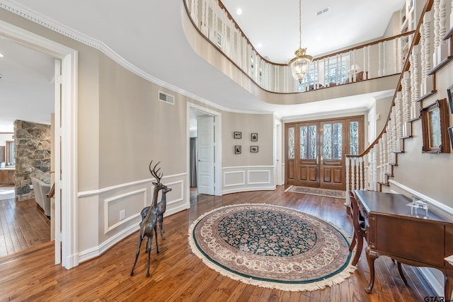 entrance foyer featuring hardwood / wood-style floors, visible vents, and crown molding