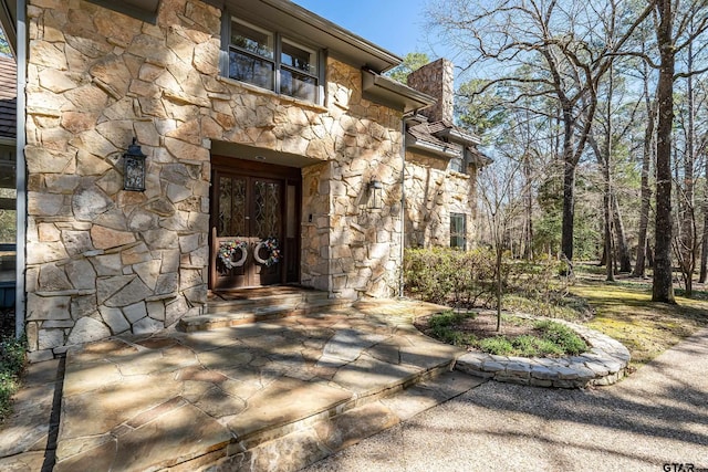 entrance to property with stone siding and a chimney