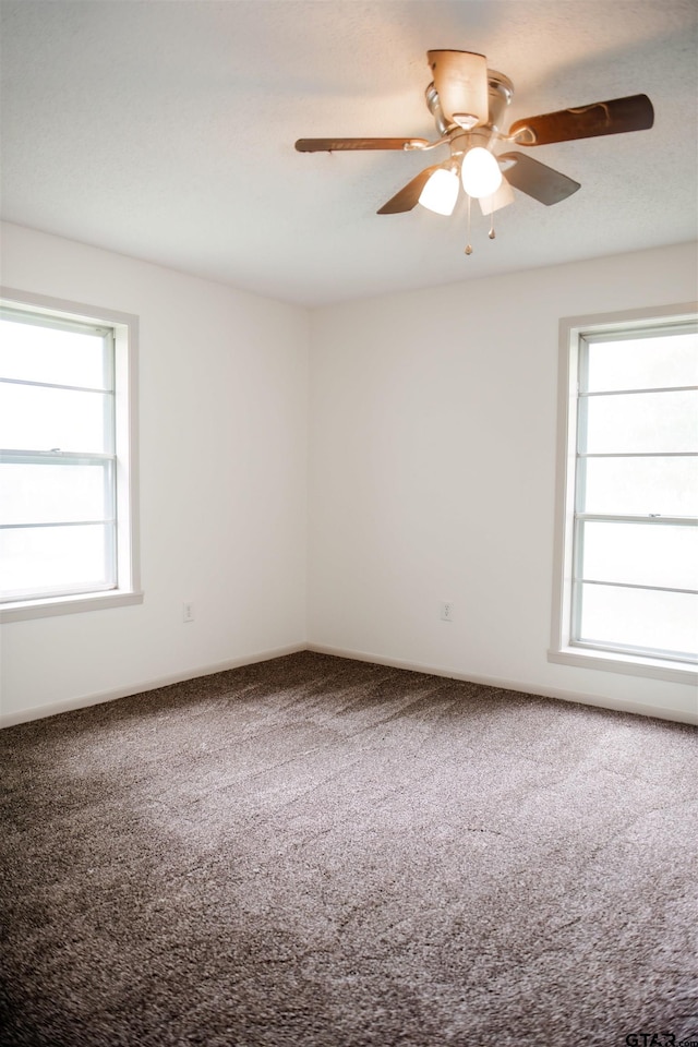 carpeted empty room with ceiling fan and plenty of natural light