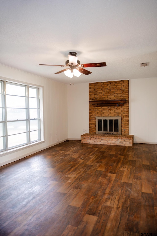 unfurnished living room featuring dark hardwood / wood-style flooring, a textured ceiling, ceiling fan, and a fireplace